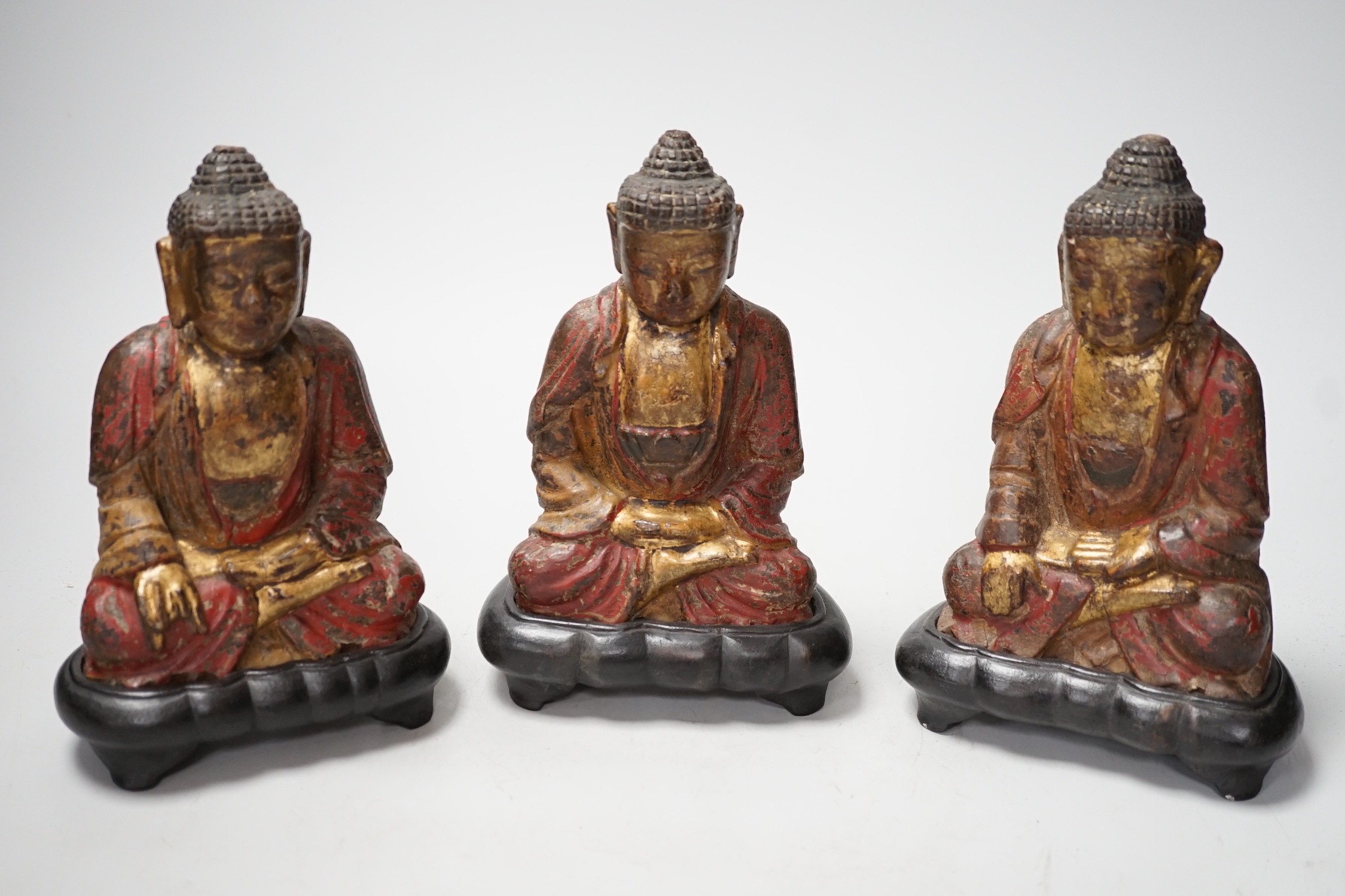 A set of three Chinese polychrome lacquered wood seated figures of Buddha, 19cm